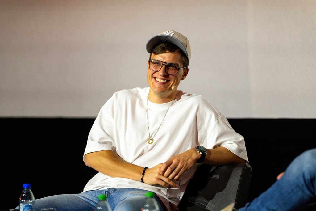 Prowadzący Podcast Biznesowy uśmiecha się podczas rozmowy na scenie